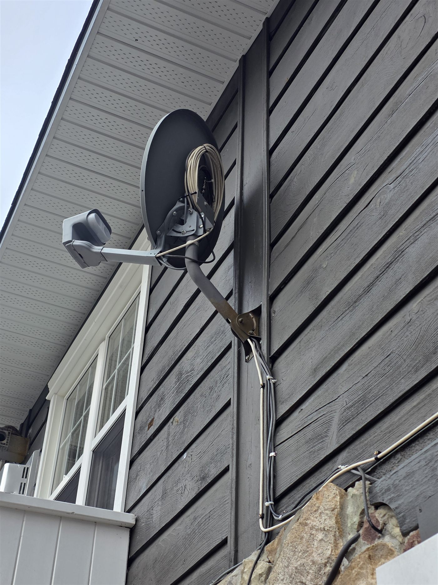 Satellite dish professionally installed under the eave of a house