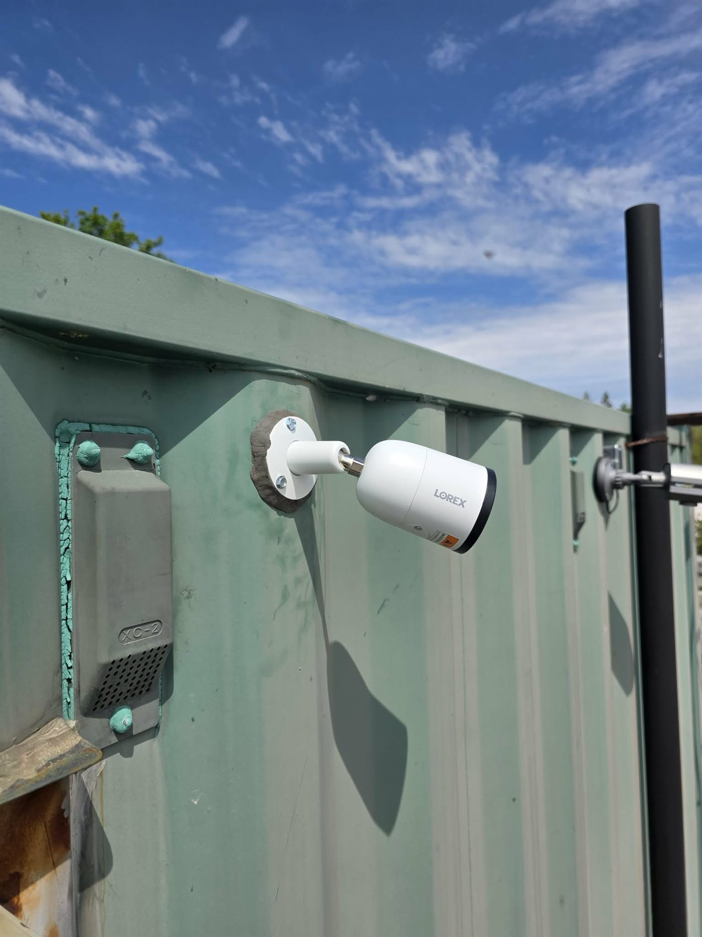 Lorex security camera installed on exterior wall against blue sky